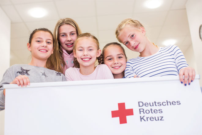 Foto: Mitarbeiter des DRK-Sanitätsdienstes blicken auf das Spielfeld im Stadion.